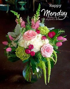 a vase filled with pink and white flowers on top of a wooden table next to a happy monday sign