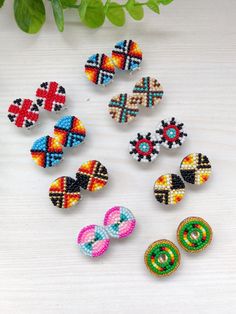 six pairs of colorful beaded earrings sitting on top of a white table next to a plant