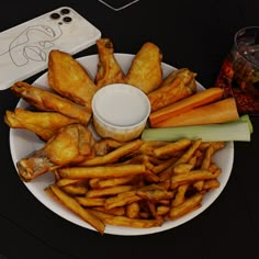 a plate full of french fries, celery and carrots with dipping sauce