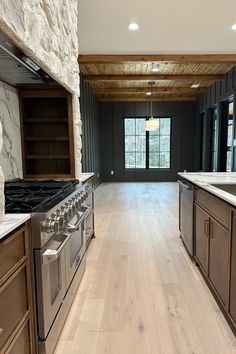 Organic Modern European Kitchen with two-toned cabinets, stone vent-a-hood, and countertop backsplash. Stone Range Hood Ideas, Modern European Kitchen, Rose Tinted Glasses, Earthy Kitchen, Guest Bathroom Design, Rock Floor, European Kitchen, Countertop Backsplash, Striped Tile