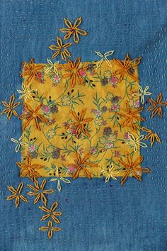 a piece of blue fabric with yellow flowers and leaves on it, stitched together