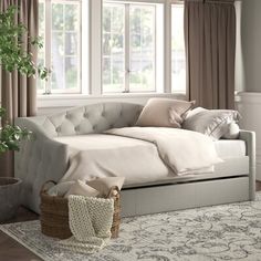 a white day bed sitting next to a window in a room with beige drapes