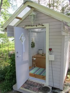 a small white shed sitting in the middle of a forest