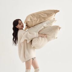 a woman is holding pillows and posing for the camera