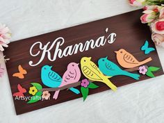 a wooden sign with birds and flowers on it