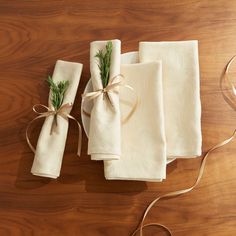 three napkins tied with twine on top of a wooden table