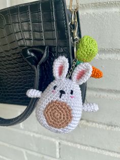 a crocheted keychain with an animal on it's side hanging from a chain