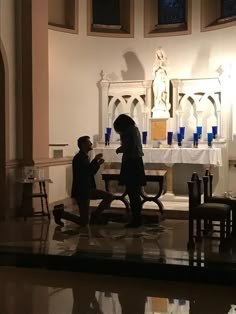 two people standing in front of a church alter with candles on the table and chairs