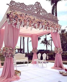 an outdoor wedding setup with pink drapes and flowers