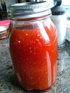 a jar filled with red sauce sitting on top of a counter