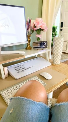 the legs of a person sitting at a desk with a computer monitor and keyboard on it