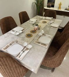 a dining room table set for six with place settings on the plates and napkins