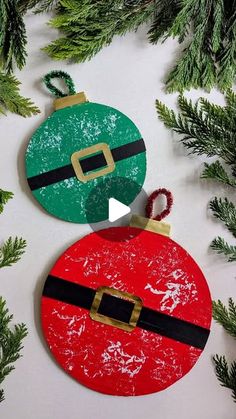 two christmas ornaments are hanging on the tree branch, one is painted red and green