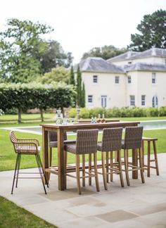 a table and chairs sitting on top of a patio next to a pool with a house in the background