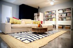 a living room with a white couch and colorful pillows on the rug in front of it