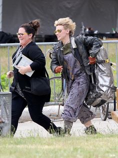 two women are walking down the street with their dogs and one is carrying a bag