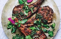 two steaks with greens and radishes on a plate