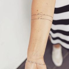 a woman's arm with a tattoo on it and a chain around the wrist