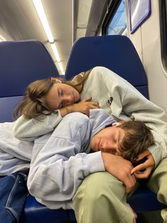 two people sleeping on a train next to each other with their arms around each other