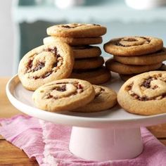 a white plate topped with cookies on top of a wooden table next to a pink napkin