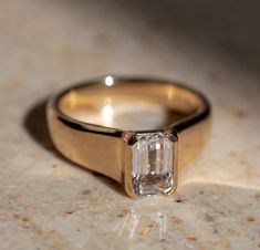 a gold ring with an emerald cut diamond