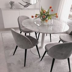 a dining table with four chairs and a vase filled with tulips on top