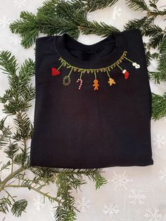 a black t - shirt with christmas decorations hanging from it's collar on a tree branch