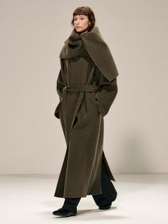 This luxurious double-breasted coat crafted from 100% wool features a versatile shawl collar that can be styled as a dramatic cape, complete with a detachable belt for a customized silhouette. The maxi-length design offers superior warmth and sophistication, while thoughtful details like side slit pockets, hidden snap closures, and a full twill lining elevate its collectible appeal. Available in both khaki and black, this handmade piece combines timeless elegance with practical functionality, ma Shawl Collar Coat, Collar Coat, Collared Coat, Double Breasted Coat, Shawl Collar, Wool Coat, Fashion Illustration, Floor Length, Double Breasted