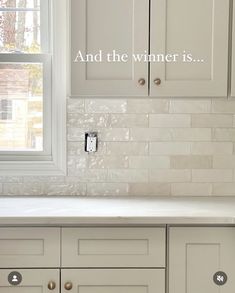 a kitchen with white cabinets and tile backsplashing that says, and the winner is