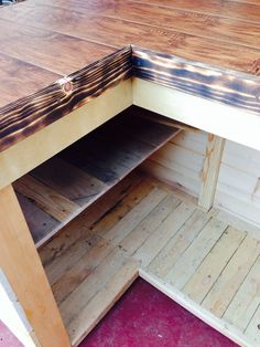 the inside of a wooden table with shelves and drawers on it's bottom shelf