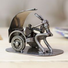 a metal figurine of a man riding a motorcycle on a wooden table next to a plate