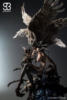 an image of a statue with wings on it's head and two skulls in the foreground