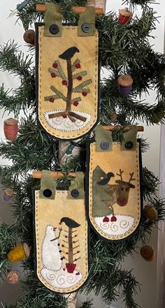 three christmas stockings hanging from a tree decorated with animals and pineconi cones on the branches