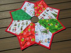 a close up of a quilted christmas star on a wooden table with wood boards in the background