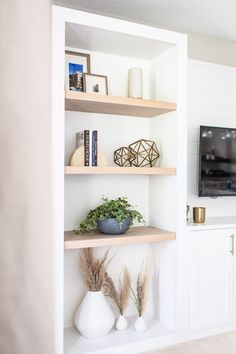 a living room filled with furniture and a flat screen tv on top of a wooden shelf