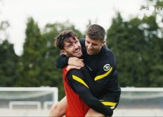 two young men hugging each other on a soccer field