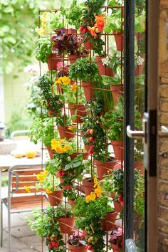 a tall planter filled with potted plants next to a patio table and chairs