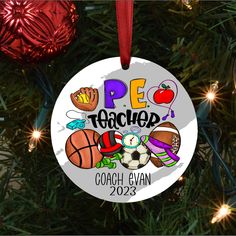 a personalized ornament hanging on a christmas tree with ornaments around it that say pe teacher coach evan