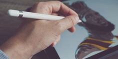 a hand holding a white pen writing on a piece of paper next to a drawing