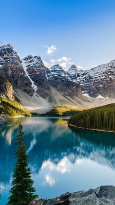 a lake surrounded by mountains and trees with snow on the tops in the middle of it