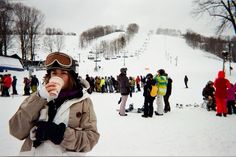 a group of people standing on top of a snow covered slope next to a ski lift