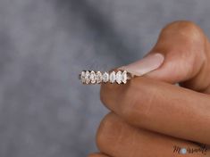 a woman's hand holding a gold ring with five diamonds on it and the middle finger