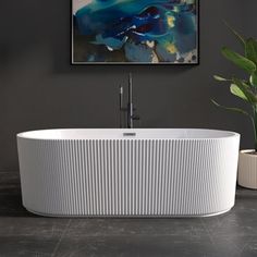 a large white bath tub sitting next to a plant