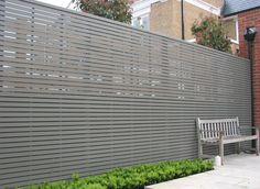 a wooden bench sitting next to a wall with vertical slats on it's sides