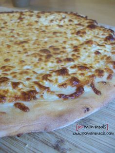 a cheese pizza sitting on top of a wooden table