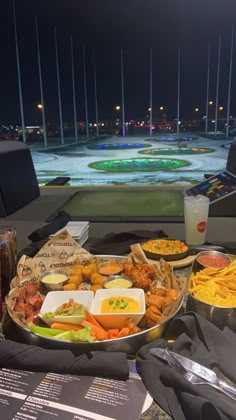 a table filled with lots of food on top of a metal tray next to a window