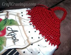 a red and white knitted purse sitting on top of a brown couch next to a striped pillow