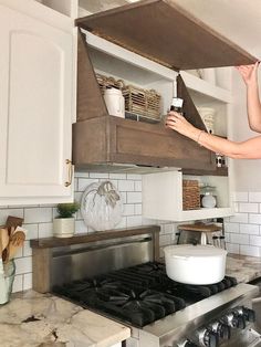 a woman is reaching for something in the kitchen