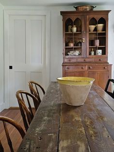 a wooden table topped with a bowl on top of it next to a hutch