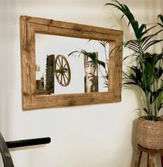 a mirror hanging on the wall next to a potted plant and a bike wheel